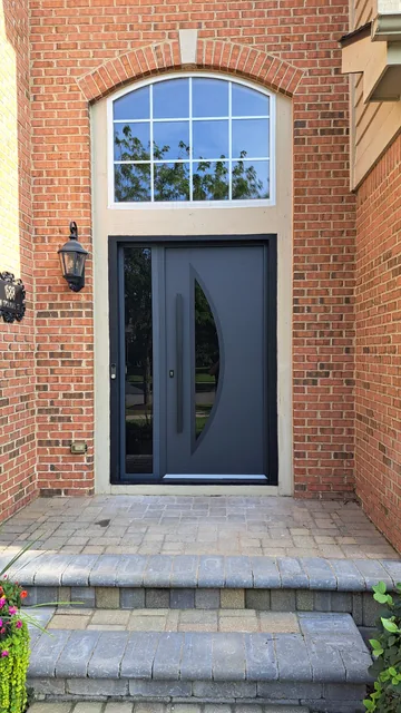 Curved-glass entry door below an arched transom